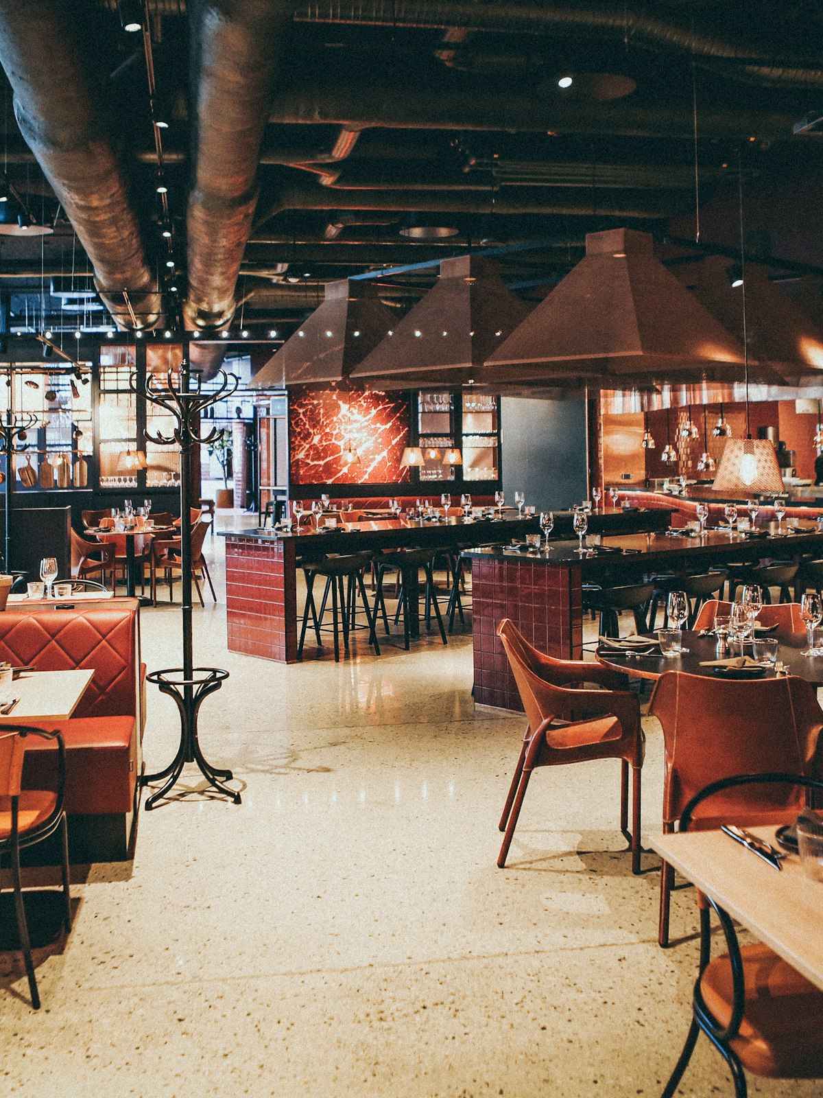 Salle de brasserie, banquettes rouges et bar en enfilade